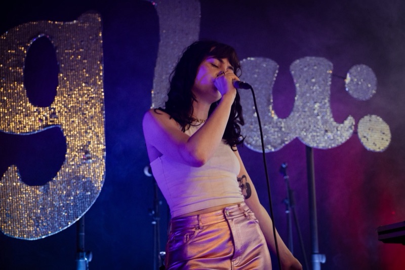 Sängerin Lotti von der Leipziger Band glu: live auf der Bühne vor dem glitzernden glu:-Schriftzug