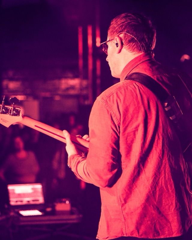 Tim, Bassist der Leipziger Band glu:, live mit Bass von hinten in rotem Bühnenlicht