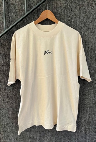 Cremefarbenes glu:-T-Shirt mit kleinem, schwarz gesticktem glu:-Logo auf der Brust